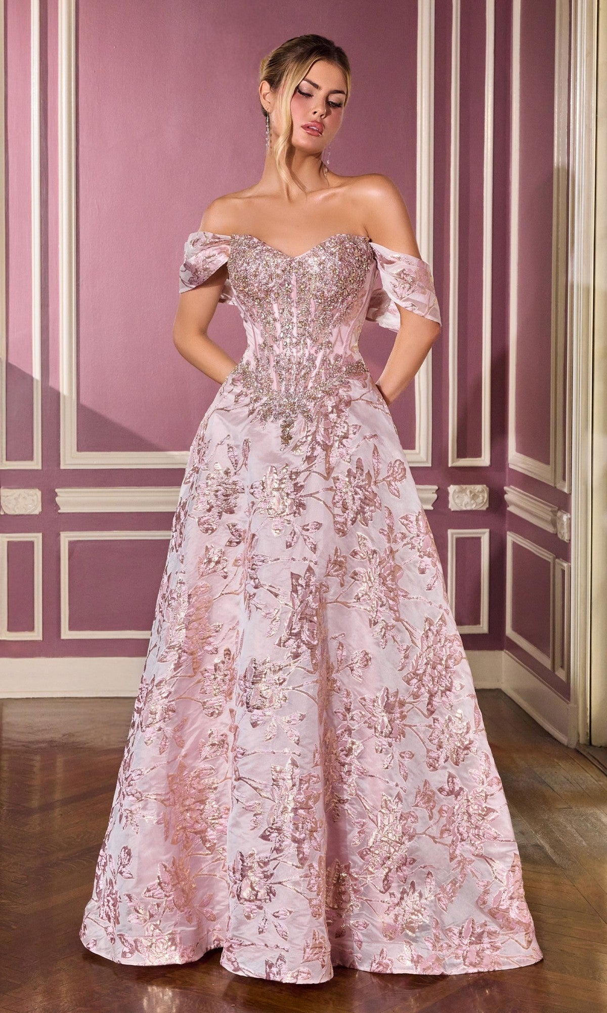 A woman in the Ladivine CD682 long prom dress in pink stands before a purple-paneled wall.
